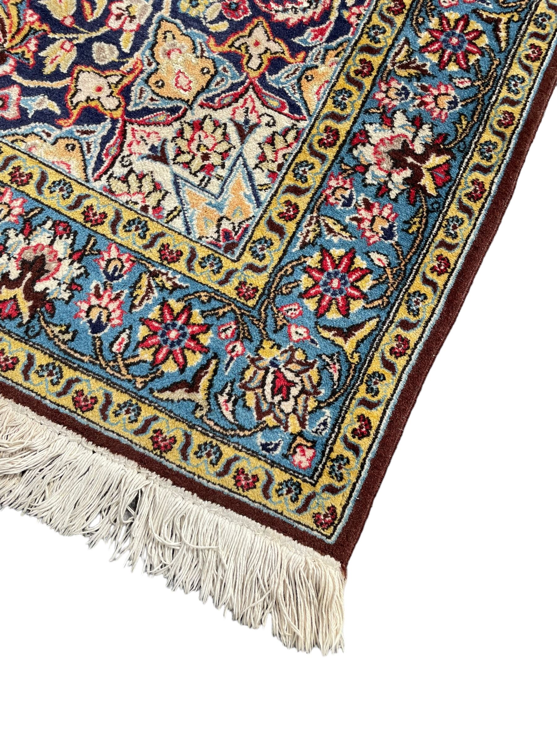 Persian indigo ground rug, overall arabesque design, central multi-point medallion surrounded by scrolling leafy branches and palmettes, the border decorated with repeating stylised plant motifs within guard stripes 