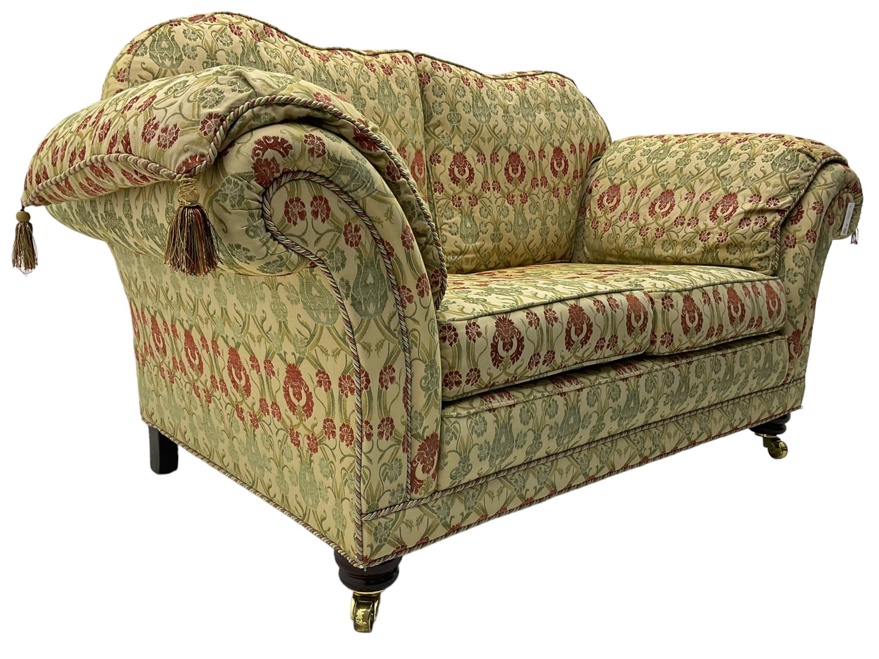 Traditional design two seat sofa, high back with scrolled arms, upholstered in beige fabric with red and green damask motifs, on castor supports (L178cm, D100cm, H89cm); matching armchair (L109cm, D89cm, H89cm)