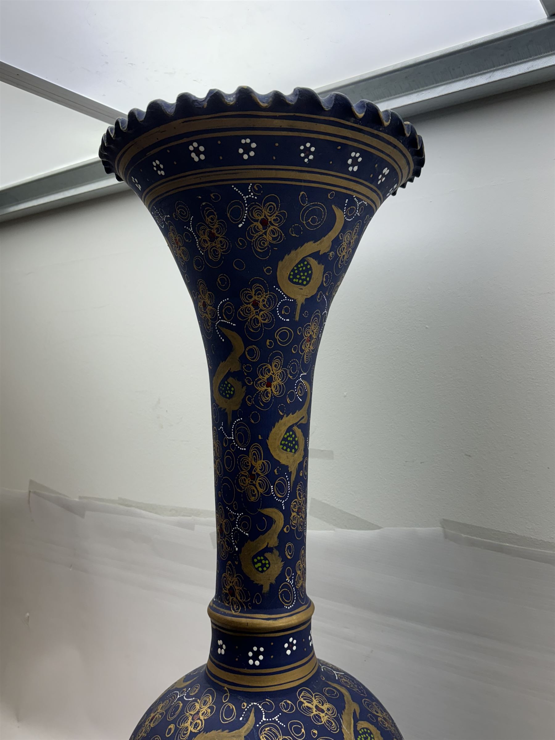 Large and unusual terracotta floor vase, of ovoid form with tall flared neck with frilled rim, decorated with stylised foliate motifs in gilt upon a dark blue ground, H89cm