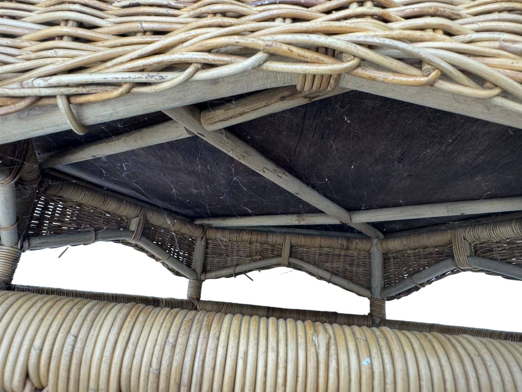 Mid-20th century hexagonal wicker coffee table, featuring woven top with pattern that radiates from the centre, lower shelf for additional storage, supported by interwoven wicker legs