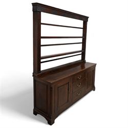 George III oak dresser, rectangular top, fitted with three central graduating cock-beaded drawers, flanked by panelled cupboards with quarter-canted pilaster uprights, lower moulded edge on bracket feet; with associated stained pine plate rack, carved with fluted detail (W170cm H124cm)