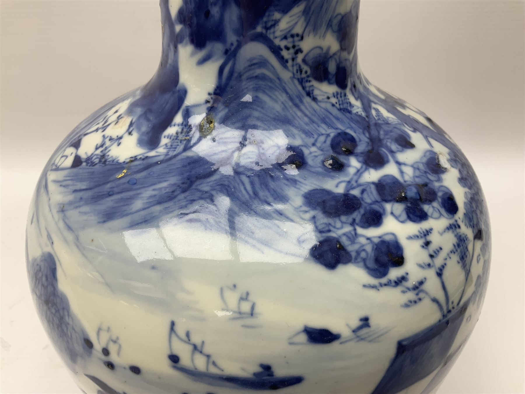 Late 18th/early 19th century Chinese blue and white bottle vase, decorated with a landscape scene containing dwellings, prunus and pine trees, boats and bridges, and populated with figures, with character mark beneath, H35cm