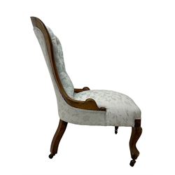 Victorian walnut nursing chair, the curved cresting rail carved with central cartouche and scroll leaves, upholstered in pale blue fabric decorated with trailing floral design, on cabriole front feet 