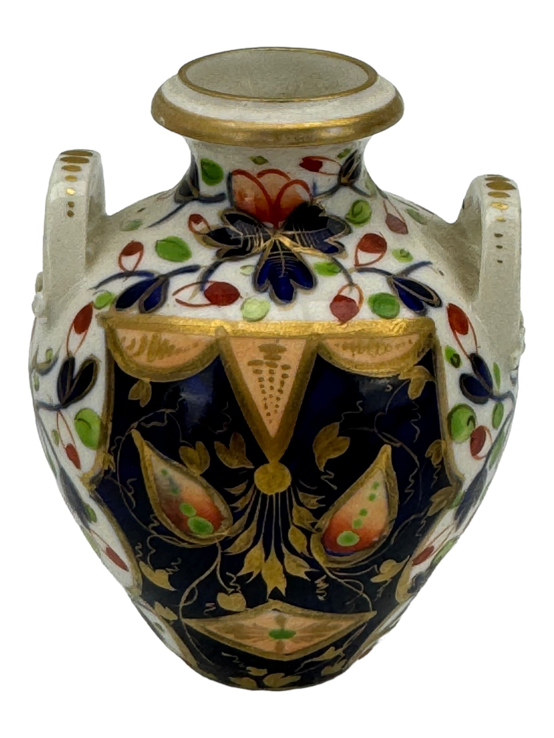 Early 19th century Derby porcelain to include a campana form inkwell, small bottle form vase, twin handled vase and flared rim vase, hand painted with a landscape scene, H10cm (4)