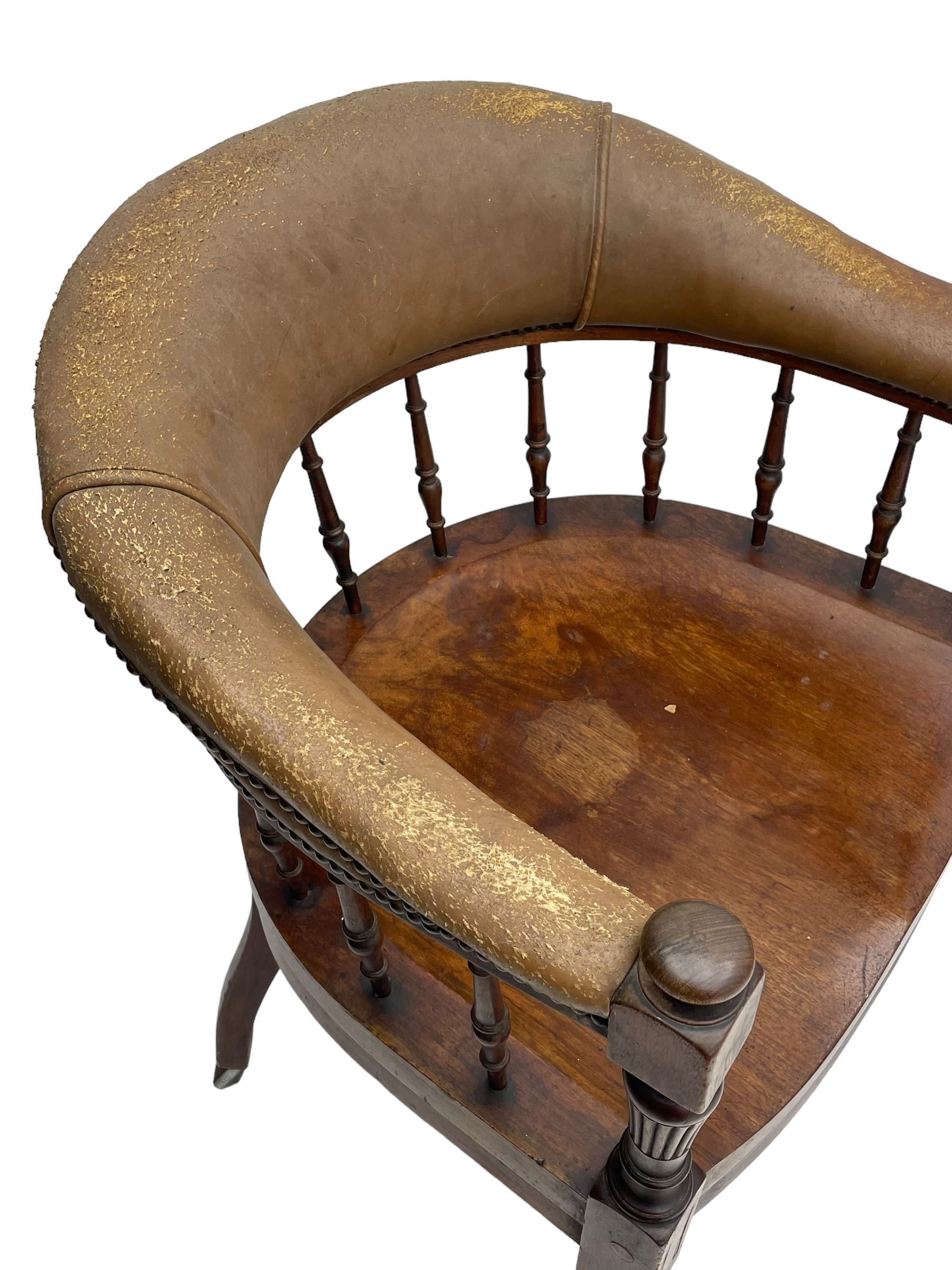 Pair of late Victorian walnut tub-shaped elbow chairs, the cushioned cresting rail upholstered in leather on spindle turned supports, dished saddle seat on turned supports