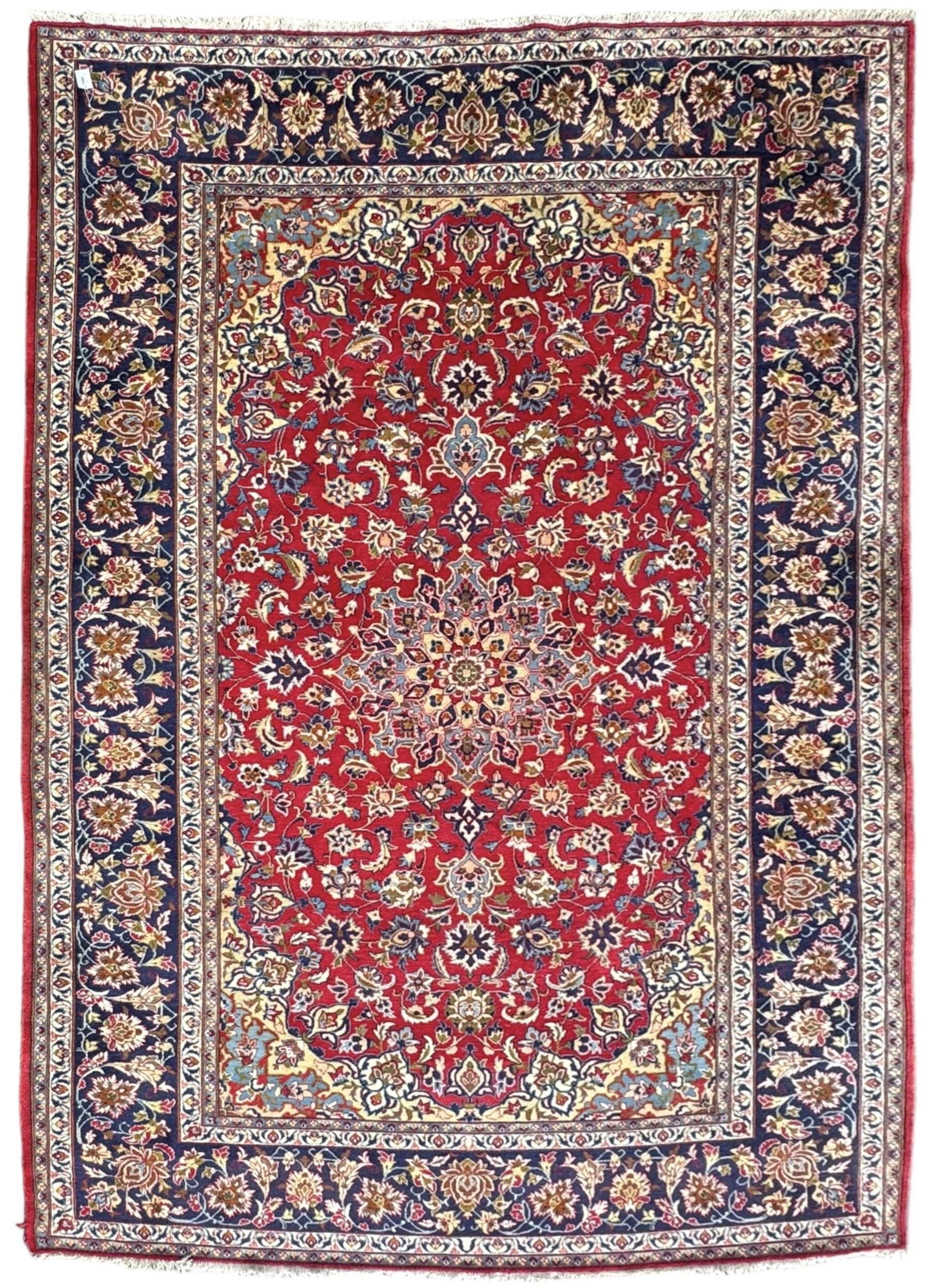 Persian Kashan red ground rug, the field decorated with a central floral medallion surrounded buy scrolling vine motifs and palmettes, the main border featuring a series of stylised floral motifs against a dark blue ground, enclosed by multiple guard stripes with alternating floral and geometric designs