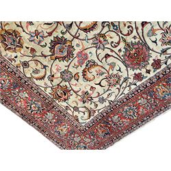 Persian Sarough ivory ground rug, the field decorated with curled leafy branches and palmettes, crimson ground border decorated with further palmettes and floral sprays, within guard stripes 