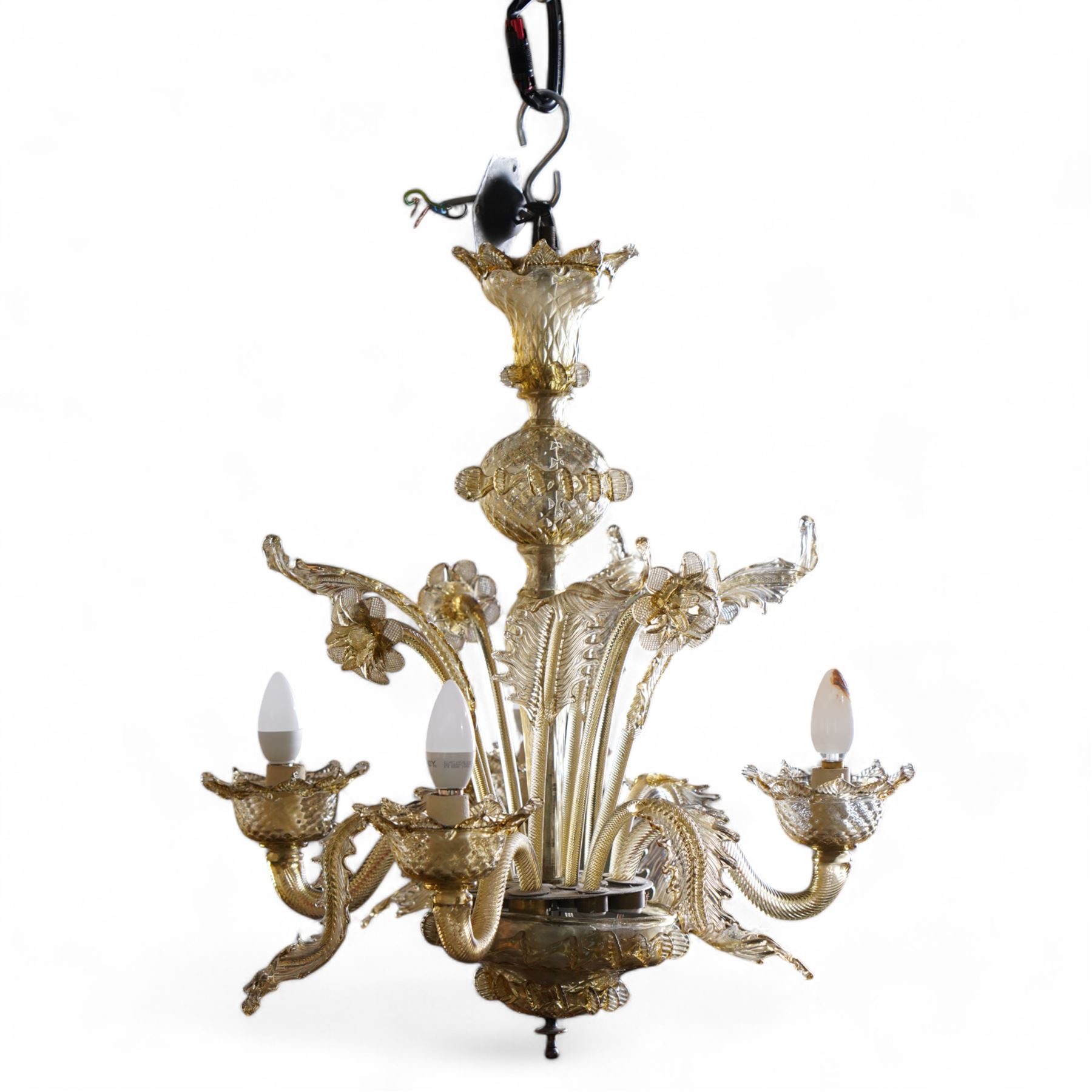 Mid-to-late 20th century Murano glass four branch chandelier, elongated baluster stem with foliate decoration, each segment with hot-work decoration, four serpentine branches interspersed with twisting acanthus leaves, each branch fitted with bobeche, surmounted by eight arms of alternating glass flowers and leaves 