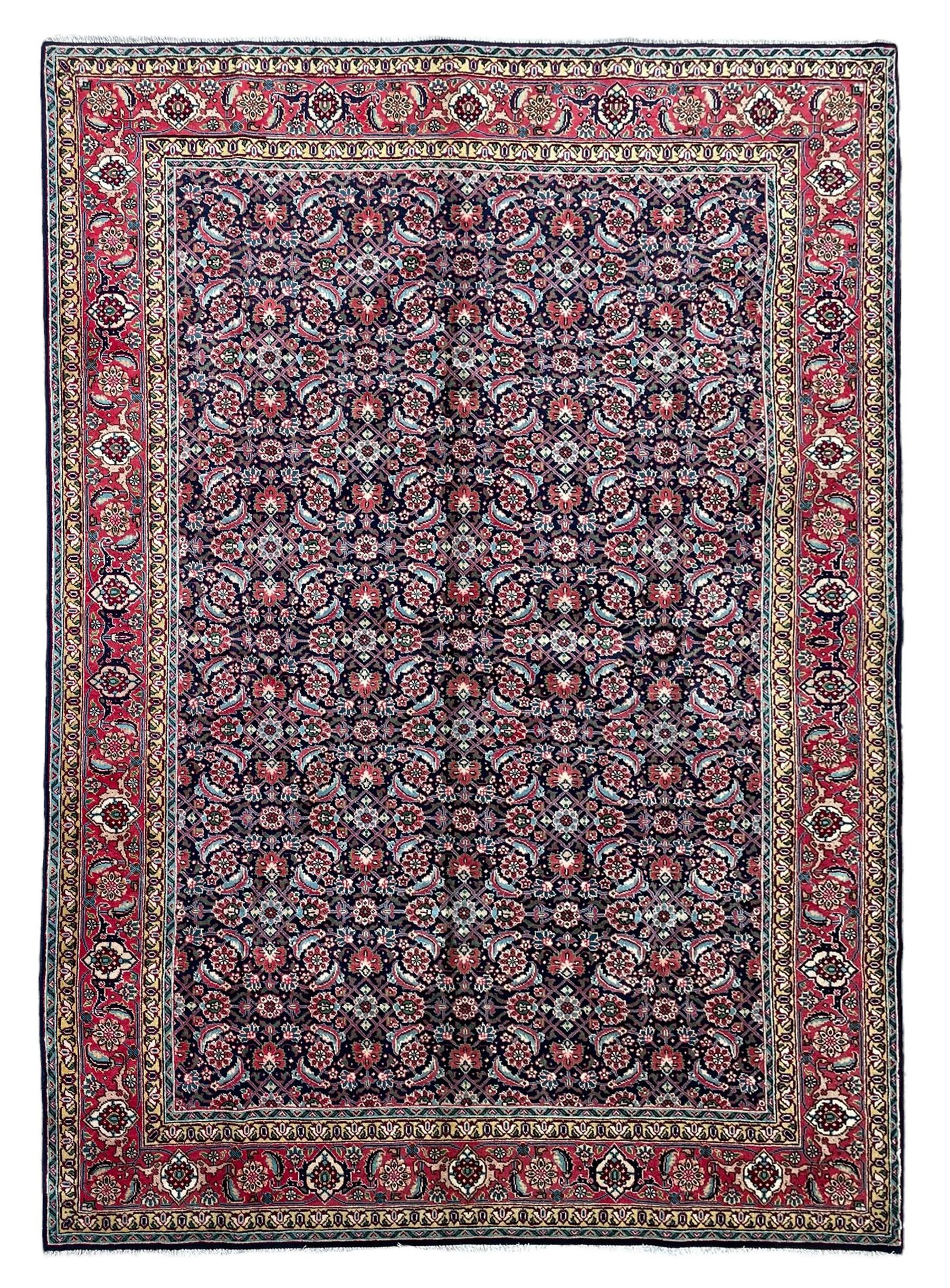 Persian Farahan indigo ground rug, the field decorated with large repeating floral herati motifs, crimson ground border decorated with palmettes and trailing leafy branch, within guard stripes 