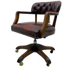 Mid 20th century leather swivel desk chair, oxblood button-tufted upholstery, wooden frame and armrests, on brass castor supports