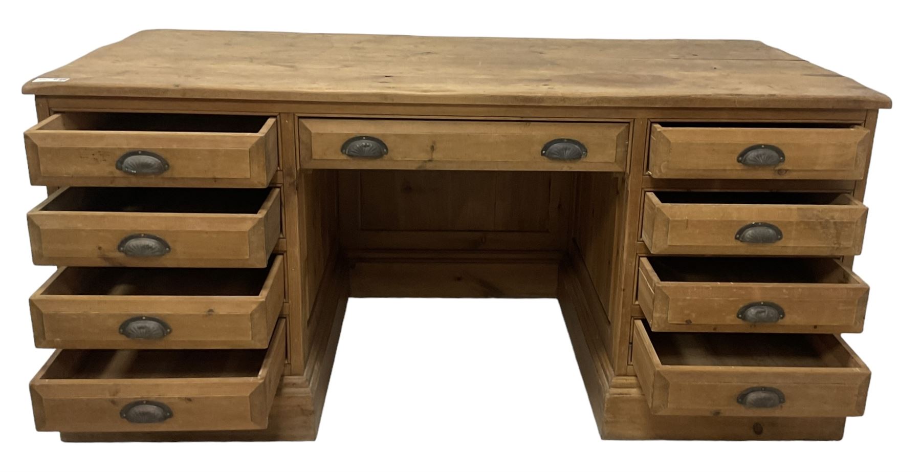 20th century waxed pine kneehole desk, rectangular top over nine drawers with cup handles, on moulded plinth base