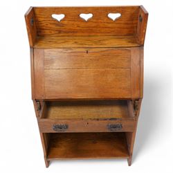 Possibly Liberty & Co - Arts & Crafts light oak bureau, the three-quarter raised gallery pierced with hearts, over a fall-front enclosing fitted interior with correspondence and pigeonholes, fitted with single drawer with poppy decorated handles, single open shelf to base