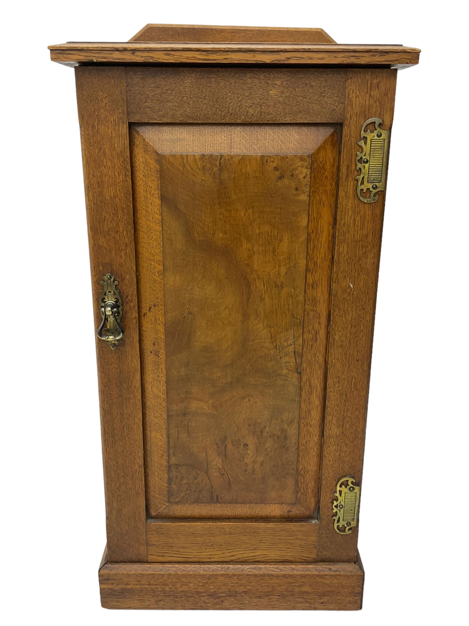 Edwardian oak bedside cabinet, raised back over moulded top, enclosed by panelled door, the interior fitted with shelves, on chamfered plinth base 