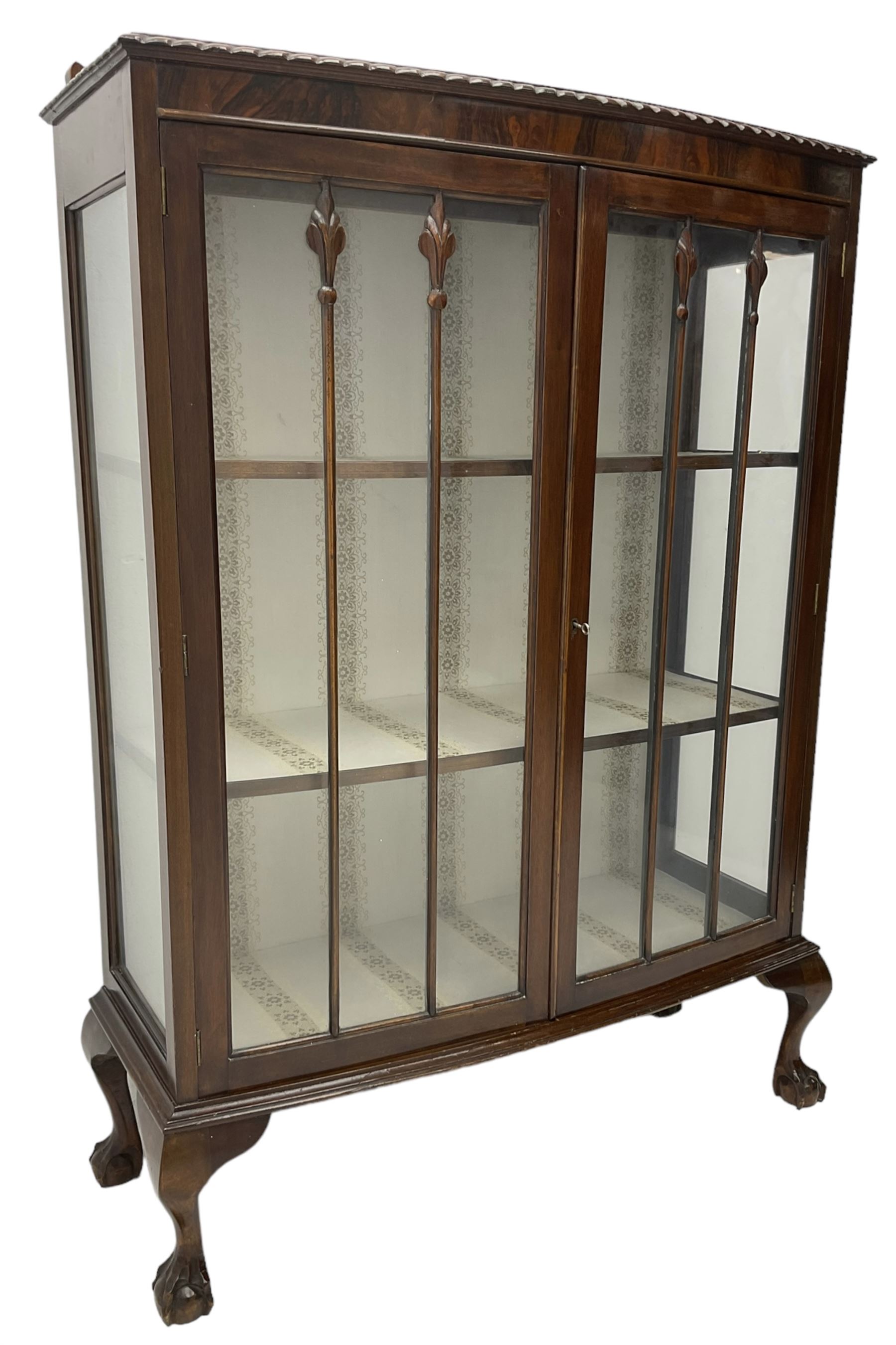 Early 20th century figured walnut bow-front display cabinet, enclosed by two glazed doors, on ball and claw cabriole feet