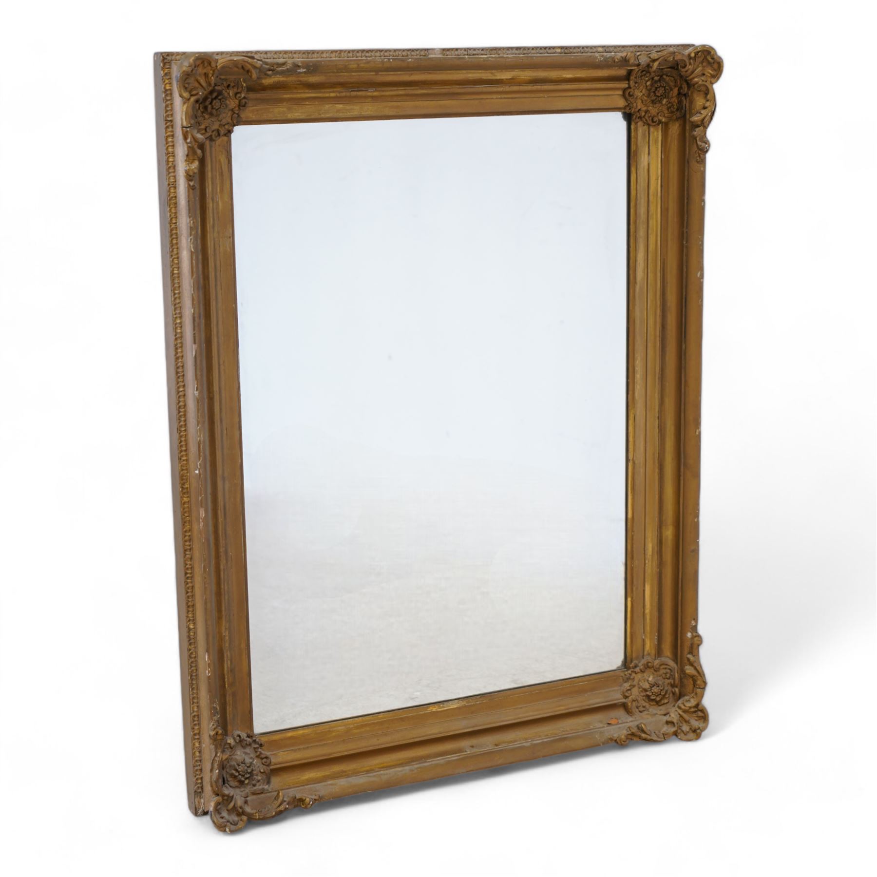 19th century gilt wood and gesso framed wall mirror, moulded rectangular swept frame, each corner decorated with floral cartouche and extending foliage, plain mirror plate 