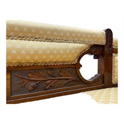 Late Victorian walnut framed chaise longue, scrolled backrest and sides upholstered in patterned yellow fabric, carved floral motifs to the backrest and sides, raised on turned supports with castors