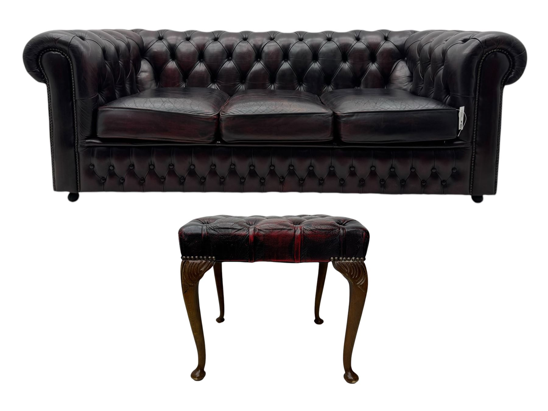 Chesterfield three-seat sofa, traditional shaped upholstered in deeply buttoned dark red leather; together with similar footstool 