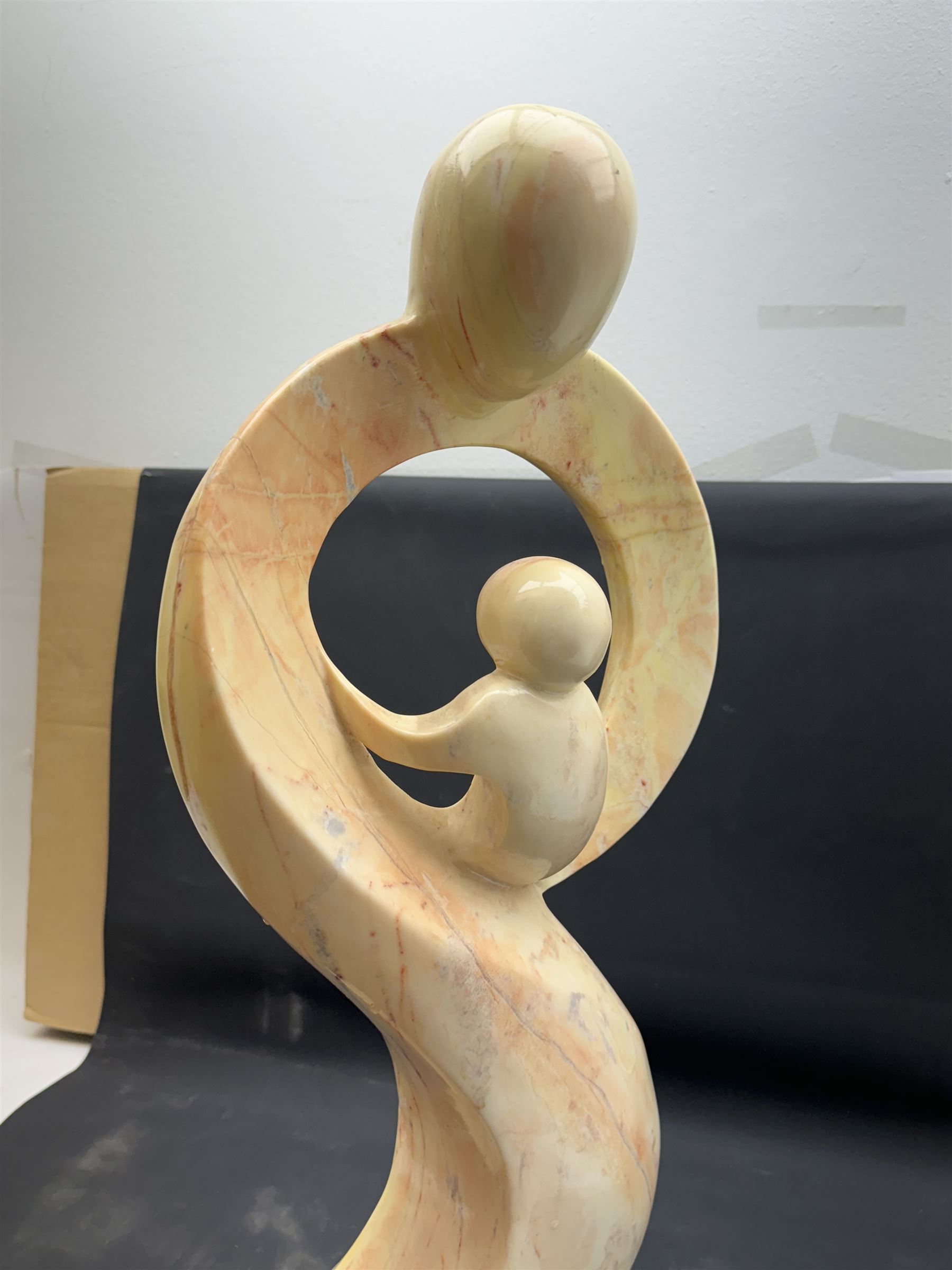 Abstract marble sculpture modelled as a mother and child on a rectangular base, H62cm