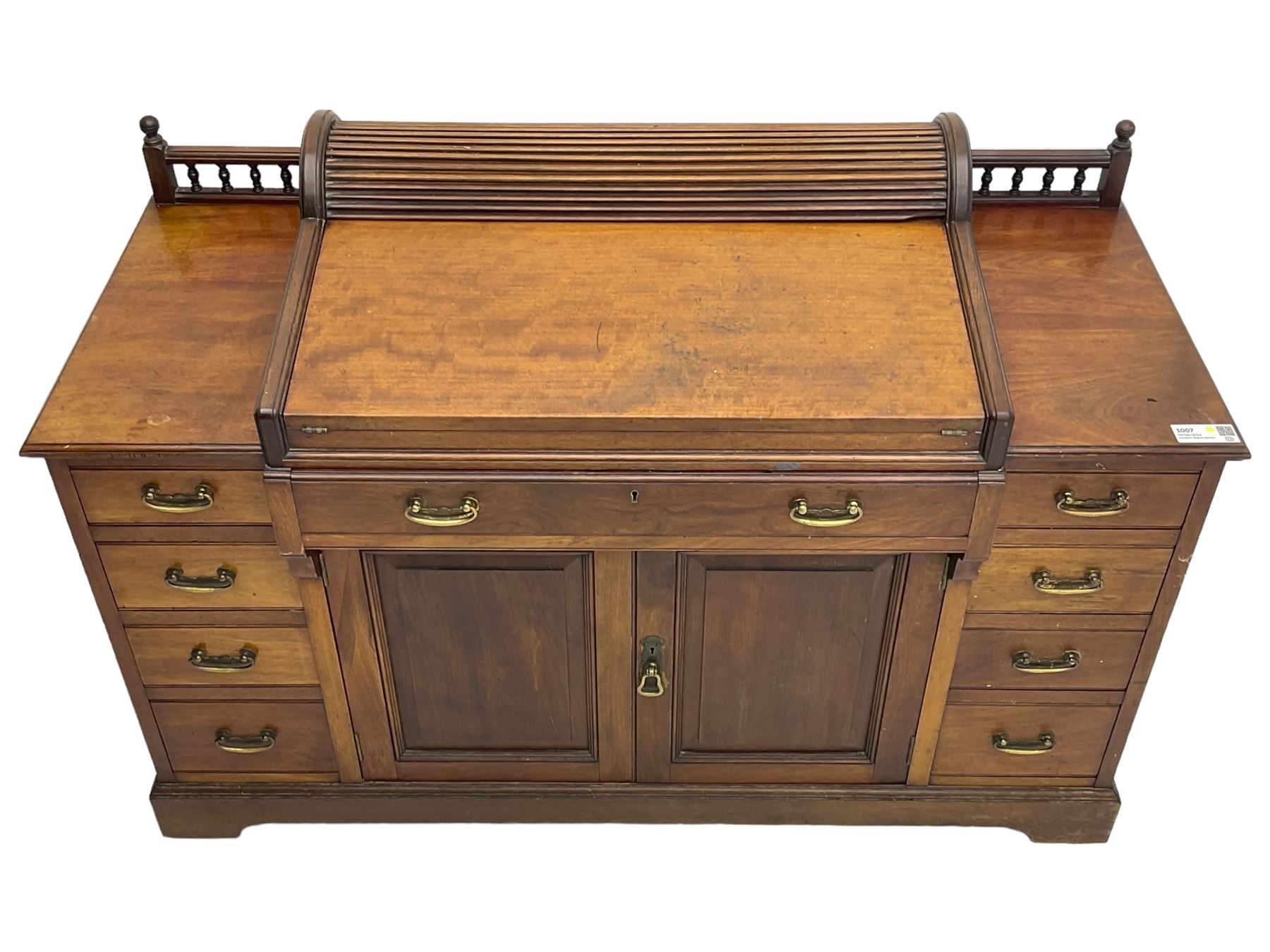 Victorian walnut clerk's desk, raised central section with tambour roll over hinged top, the interior fitted with leather inset writing surfaces, small drawers, document divisions and pen and ink stand, central drawer over double panelled cupboard, flanked by two banks of four graduating drawers, on bracket feet 