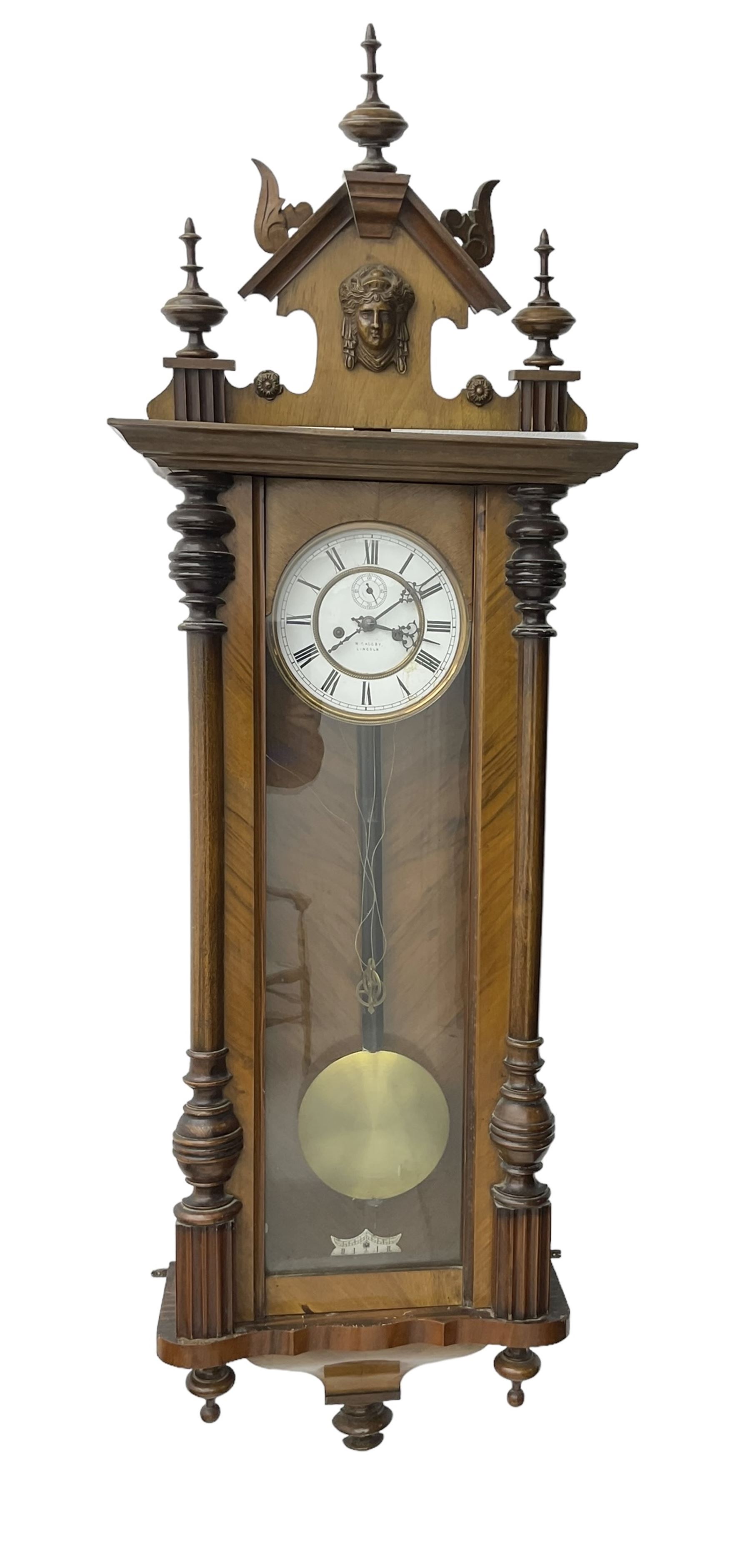 German - late 19th century walnut and ebony twin train weight driven Vienna regulator, with a fully glazed door, shaped pediment with carved pilasters and turned finials, two part enamel dial with Roman numerals, seconds dial and gothic steel hands, brass faced pendulum bob with an ebonised wooden rod and two brass cased weights, movement with a dead-beat escapement and rack striking on a coiled gong.