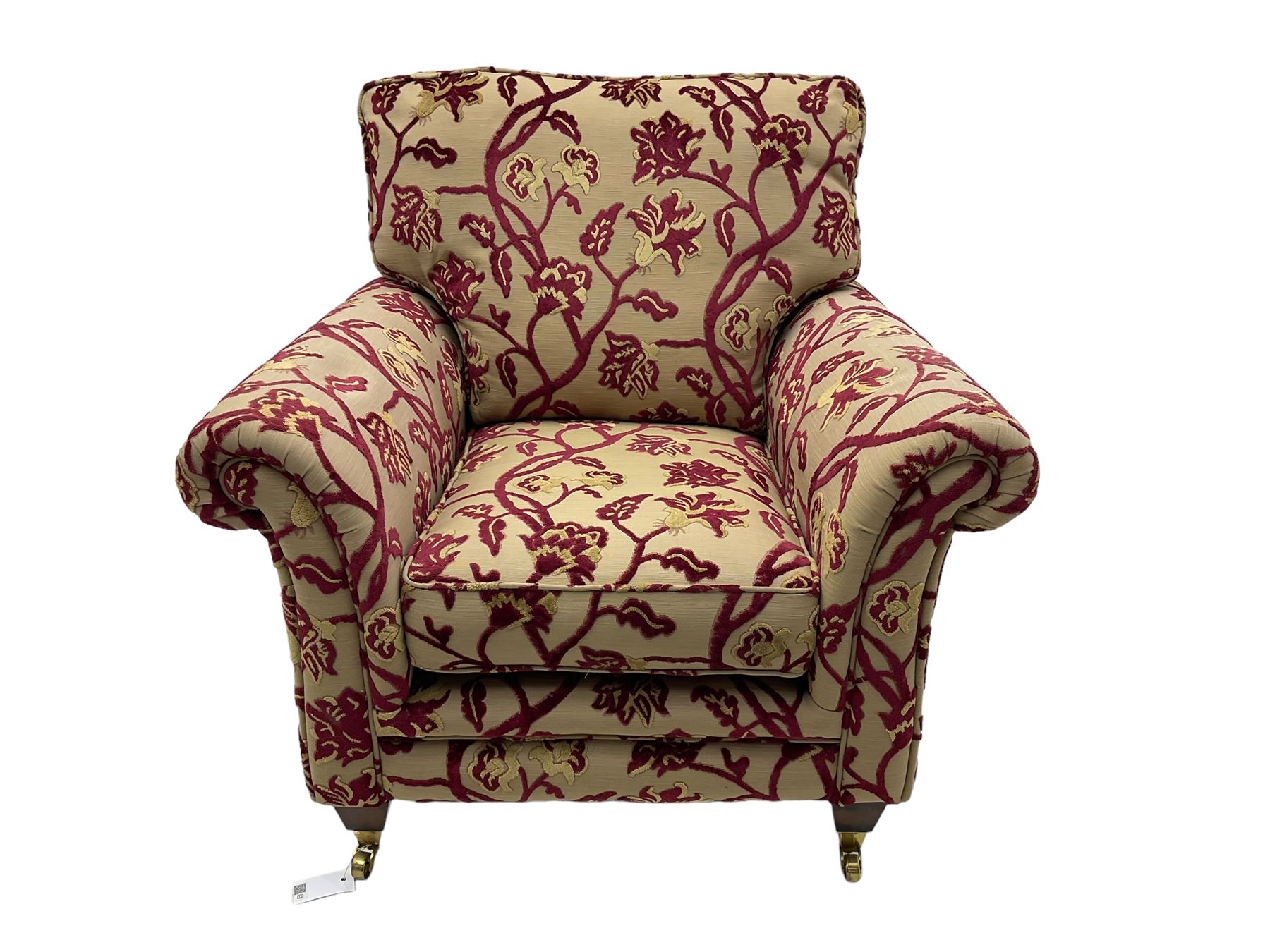 Contemporary upholstered armchair, scroll arms and loose cushions, embossed beige ground fabric with red and gold floral motifs, on tapered wooden supports with front brass castors