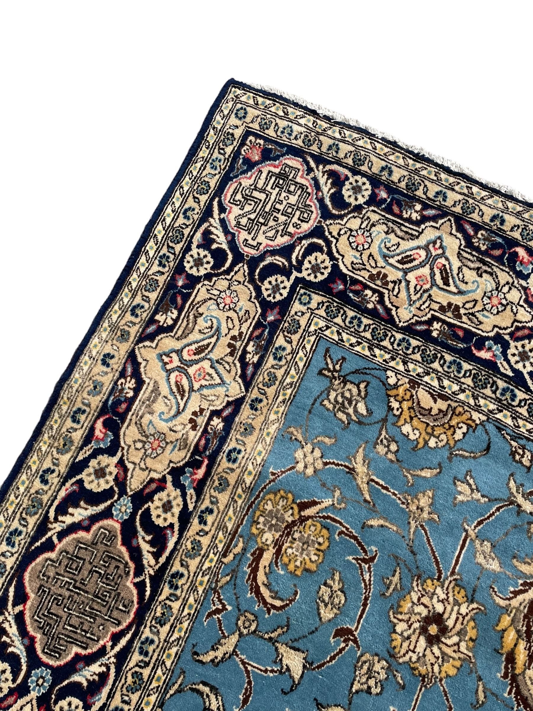 Persian Nain blue ground rug, overall arabesque design, the busy field decorated with interlacing branches and palmettes, indigo ground border with panels decorated with knots and lotus flower motifs, surrounded by trailing branches and flower heads, within guard stripes