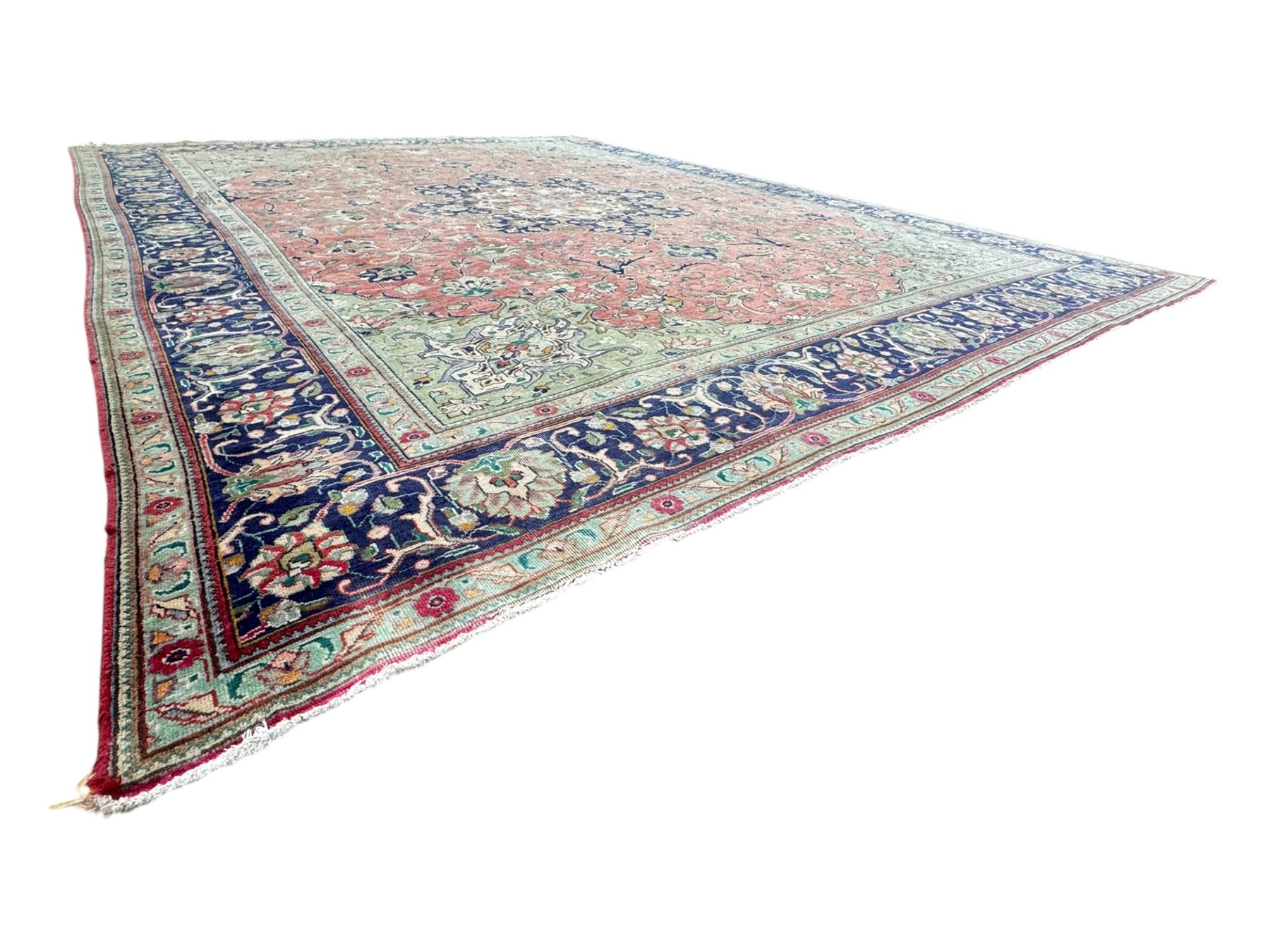 Persian rose ground rug, large central floral medallion surrounded by scrolling foliate and floral motifs, pale green spandrels, wide border in pale green and navy with intricate floral designs, framed by multiple guard stripes with repeating floral and geometric patterns