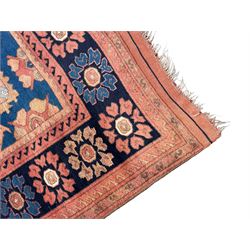 Afghan rust ground carpet, large central lozenge medallion decorated with stylised plant motifs, running water guard stripes enclosing indigo ground border decorated with stylised flower heads