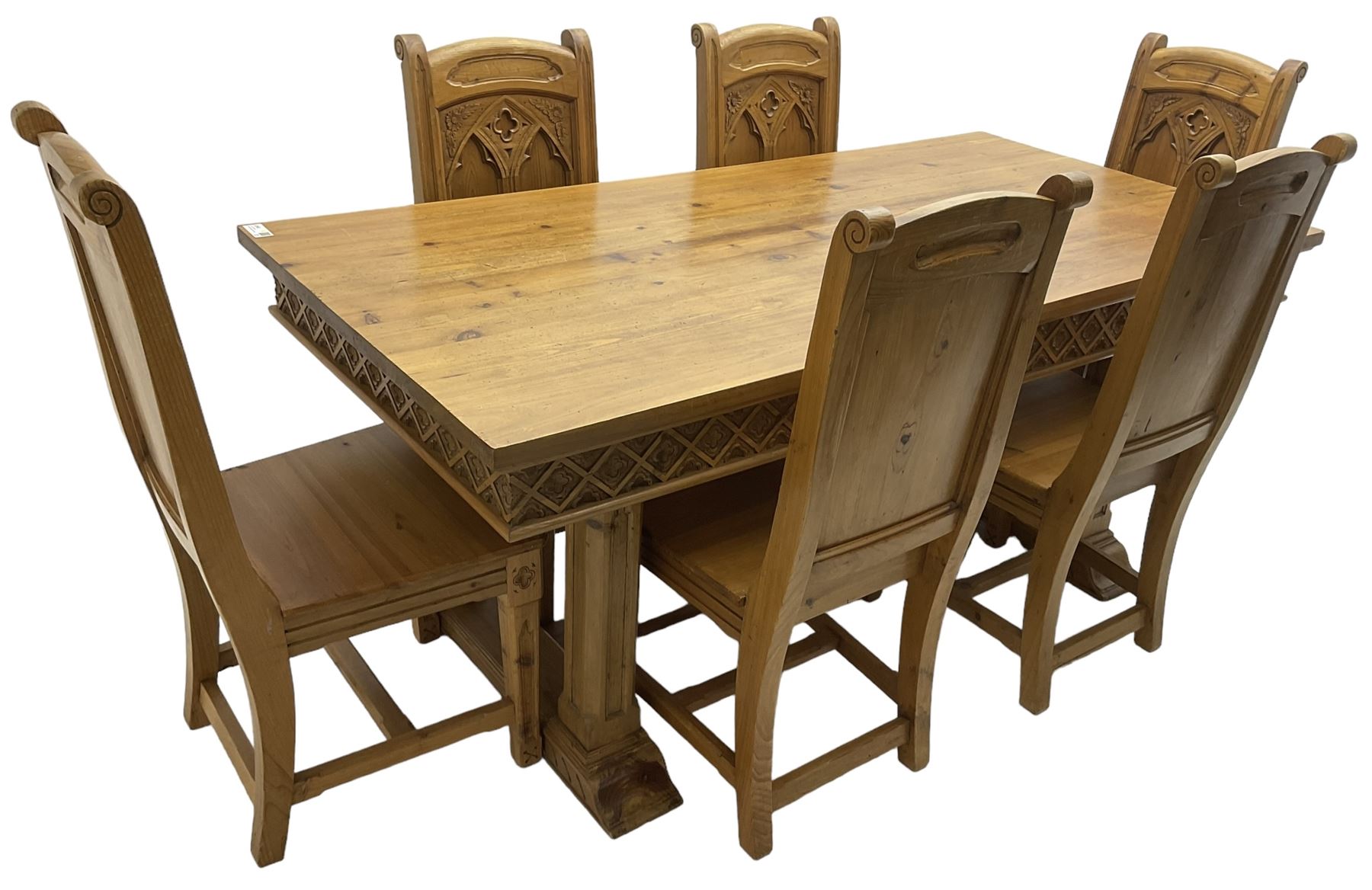 Ecclesiastical Gothic design waxed pine dining table, rectangular top over frieze carved with lattice pattern, raised on square chamfered supports with tracery style carving, on sledge feet joined by stretcher (W185cm D90cm H77cm); and set six matching chairs, high panelled back with carved and moulded gothic tracery window decoration and flower heads, panel seat over carved frieze rail and square tapering supports (W48cm H104cm)