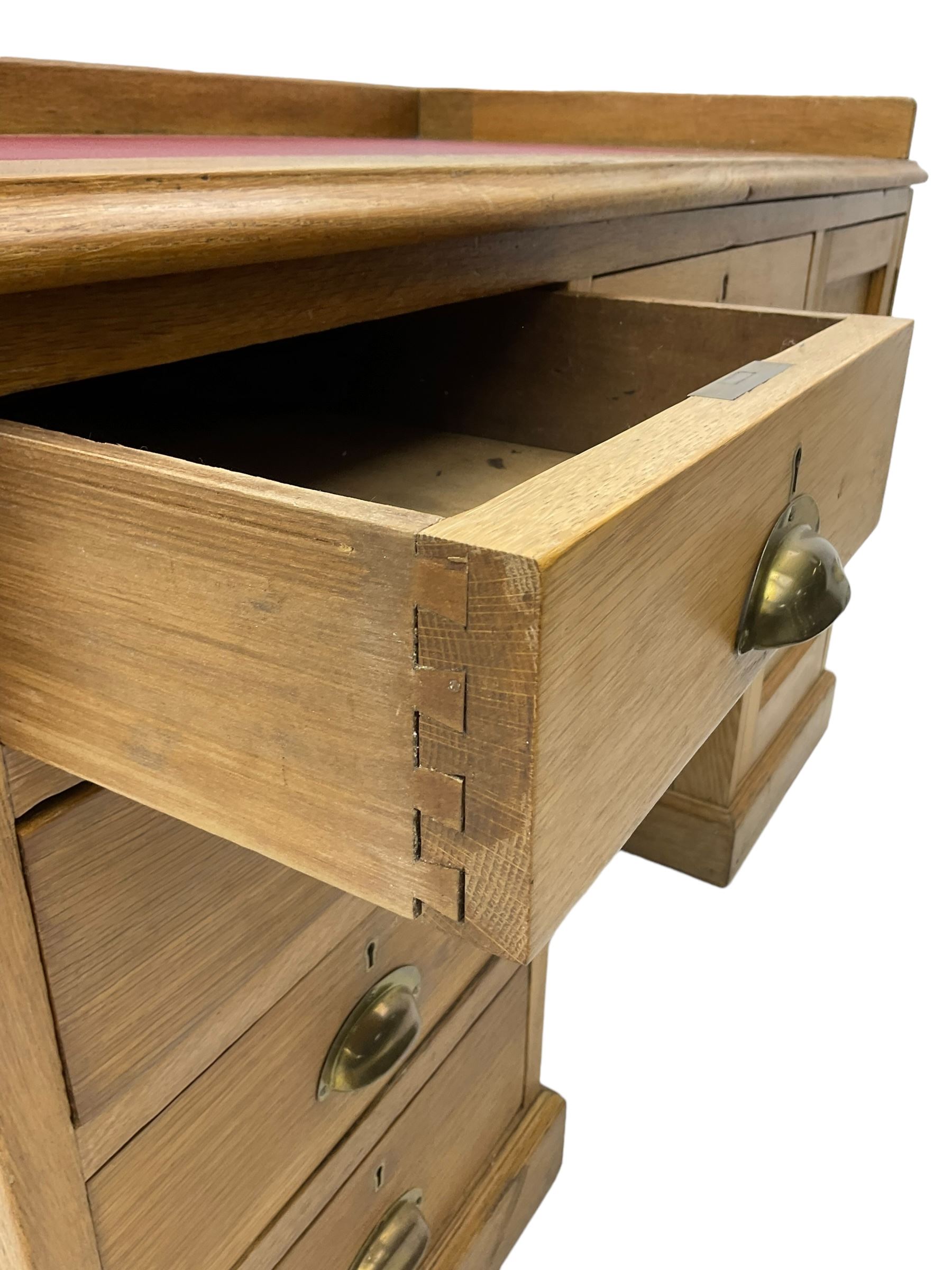 20th century oak desk, moulded rectangular top with raised back and inset leather writing surface, fitted with five drawers and single panelled cupboard, on moulded plinth base