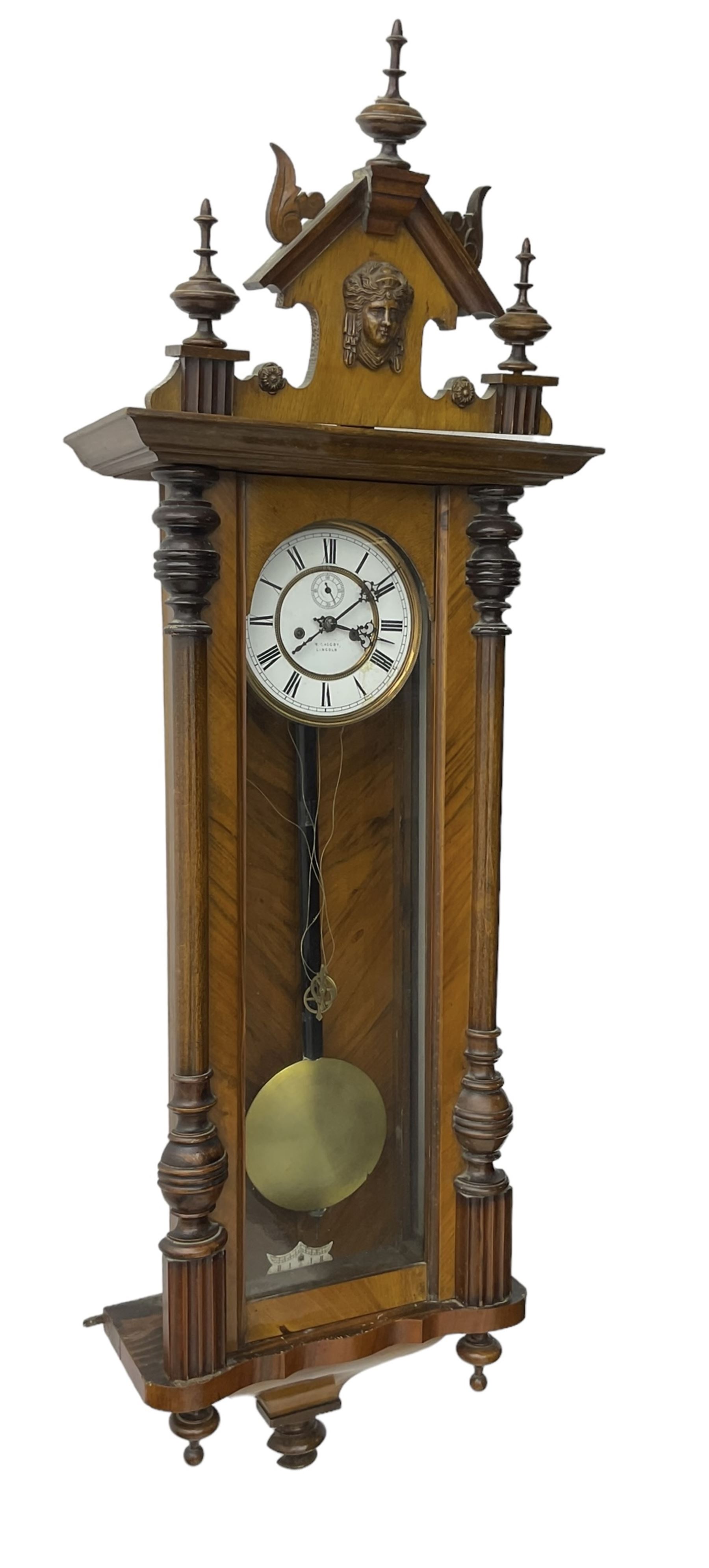 German - late 19th century walnut and ebony twin train weight driven Vienna regulator, with a fully glazed door, shaped pediment with carved pilasters and turned finials, two part enamel dial with Roman numerals, seconds dial and gothic steel hands, brass faced pendulum bob with an ebonised wooden rod and two brass cased weights, movement with a dead-beat escapement and rack striking on a coiled gong.