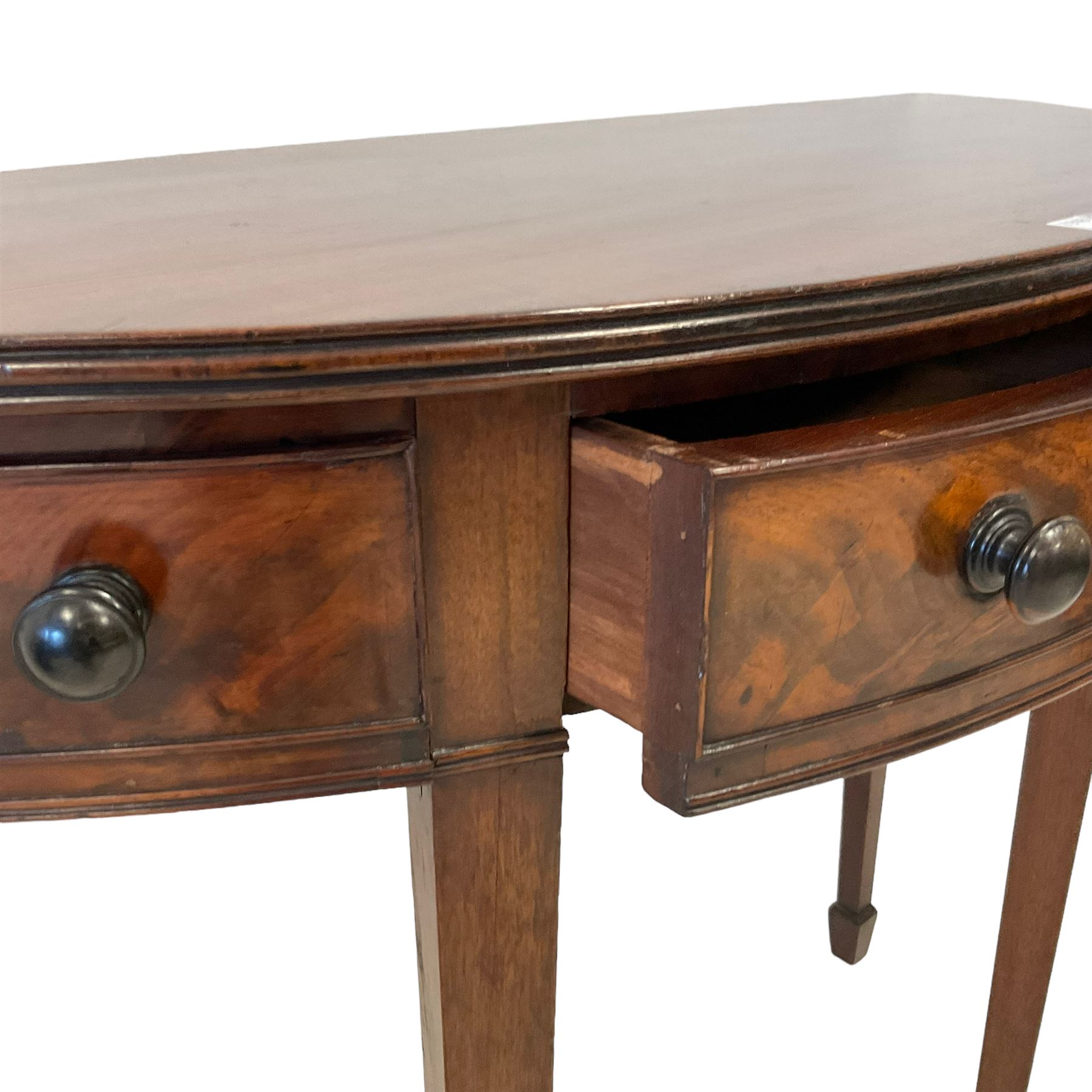 George III mahogany demi-lune side or console table, reeded edge over central frieze drawer flanked by two hinged drawers with cock-beaded facias and turned handles, raised on square tapering supports with spade feet, the rear supports and feet chamfered in profile