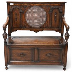 Early 20th century oak hall bench, circular caned back enclosed by panels decorated with flowerhead carved arcades, hinged box seat, panelled front 