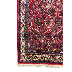 Small Persian red ground rug, the field decorated with an overall floral design, guarded ivory ground border decorated with trailing flower heads and foliage