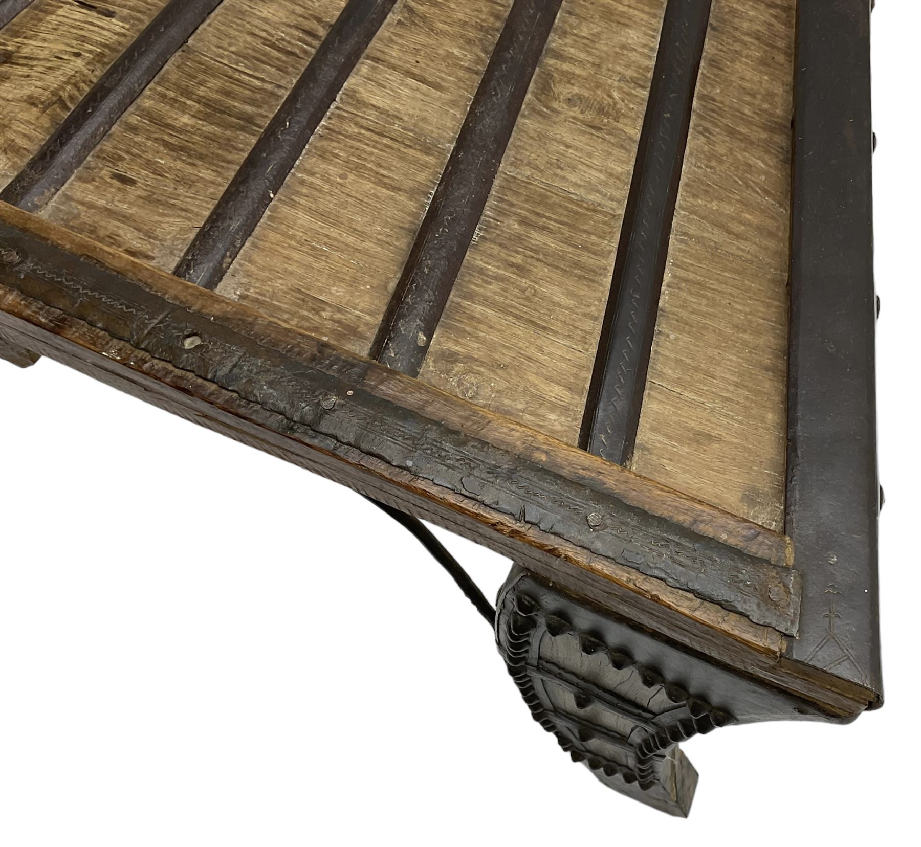 19th century Indian bullock / ox cart converted coffee table, trapezoidal top with applied metal decoration and iron stretchers, raised on three swept supports with stud decoration