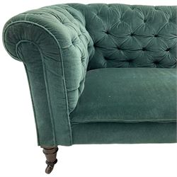 Victorian hardwood-framed Chesterfield sofa, traditional shape with low back and rolled arms, upholstered in teal buttoned fabric, on turned front feet with brass and ceramic castors 