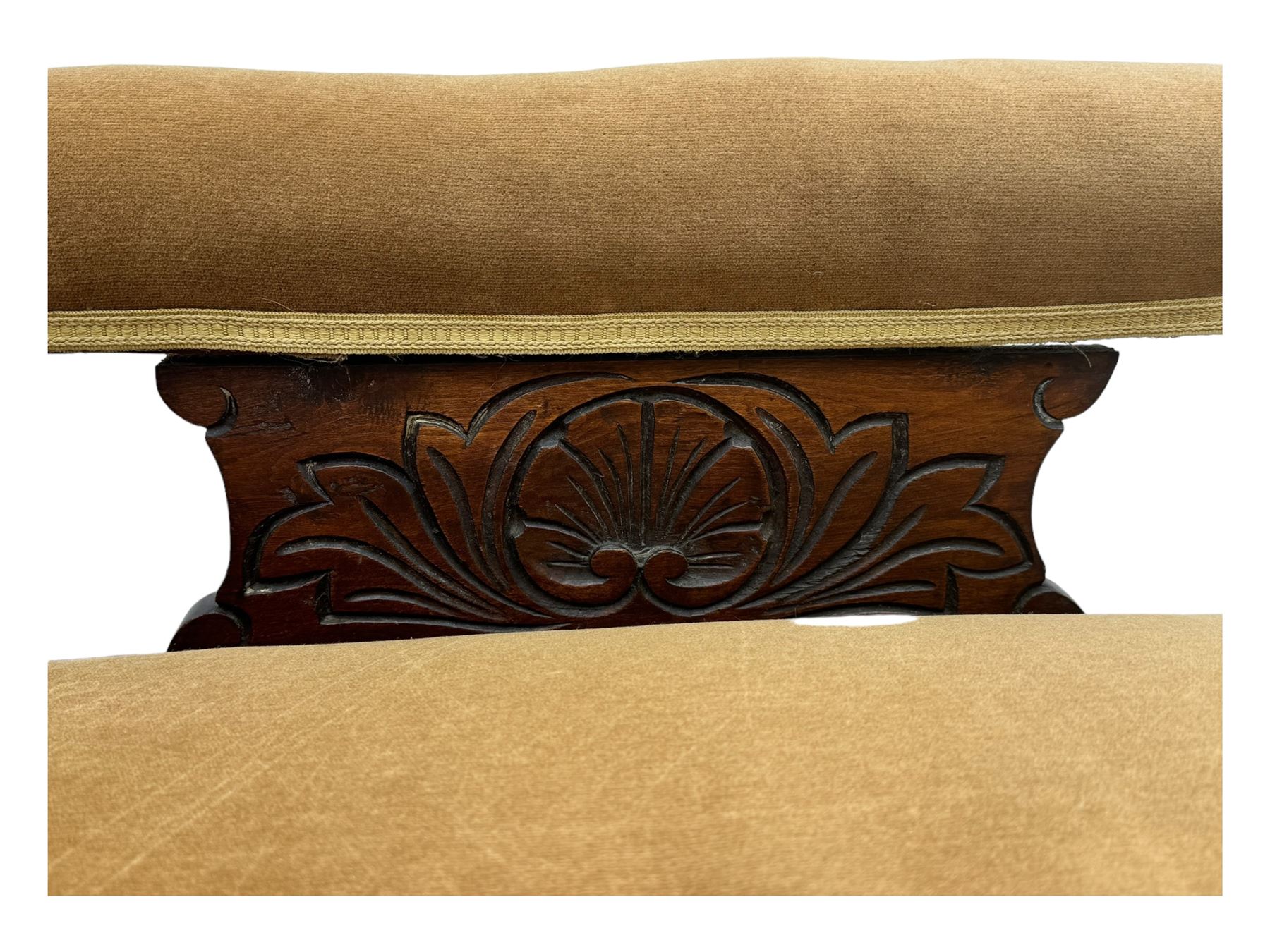 Late 19th century mahogany framed chaise longue, upholstered in tan fabric, featuring scrolled backrest with carved floral motifs, supported by turned legs