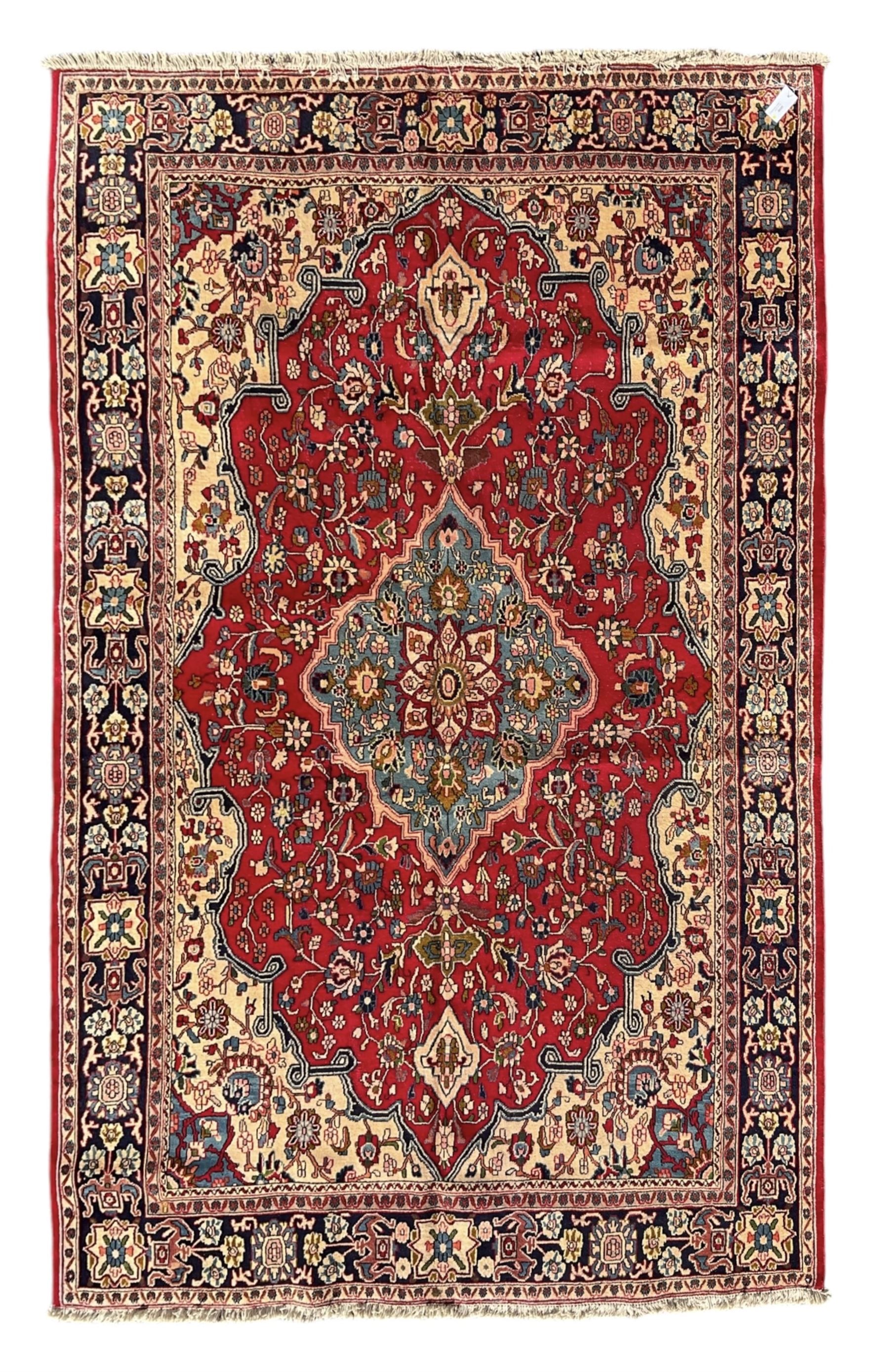 Central Persian Isfahan crimson ground carpet, central floral medallion in ivory and blue, set within a field of dense floral patterns, bordered by a navy band decorated with stylised flower heads and vines