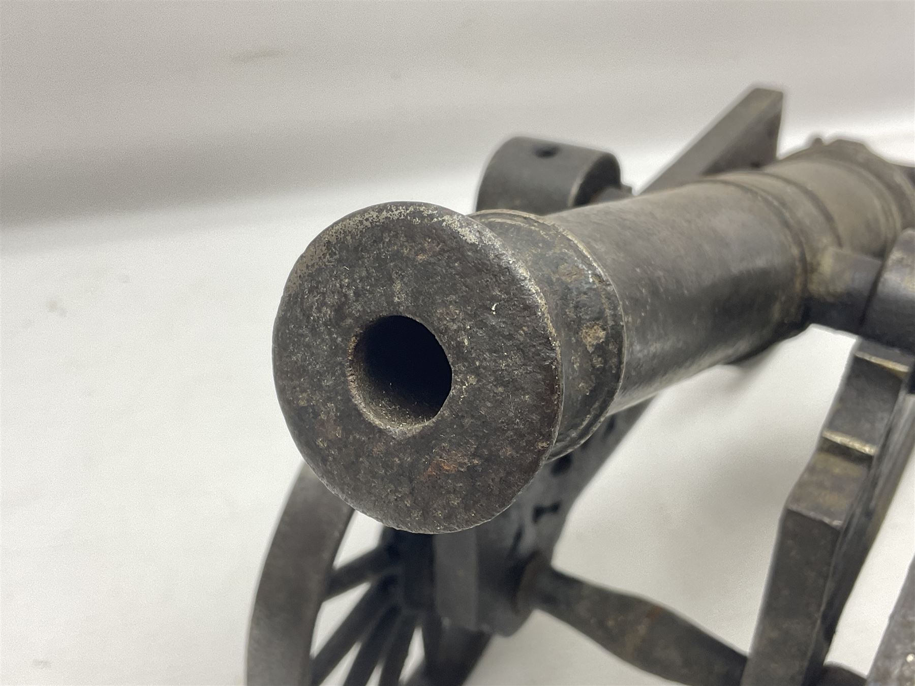 Victorian cast-iron and steel signal cannon, approximately half-inch bore, with 23cm ringed barrel and cylindrical trunnions, on a cast iron carriage with two twelve-spoked wheels and guilloche pierced swept back support, L43cm overall