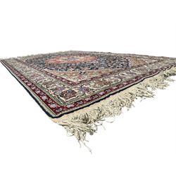 Indo-Persian indigo ground rug, the floral design peach medallion surrounded by trailing and interlaced branches and flower heads, the main border decorated with repeating stylised plant motifs within floral guard stripes 