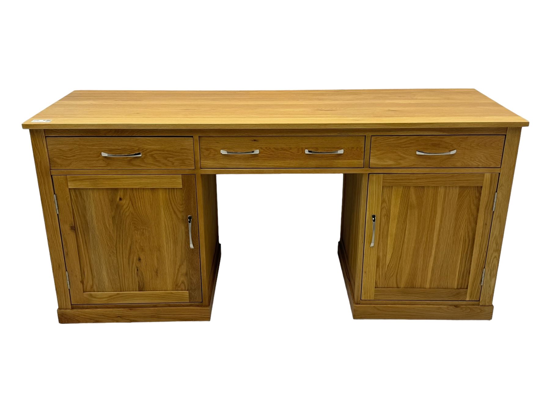 Contemporary light oak twin pedestal desk, fitted with three drawers over two cupboards with chrome handles, the central drawer with hinged front panel revealing pull-out keyboard tray, on plinth base