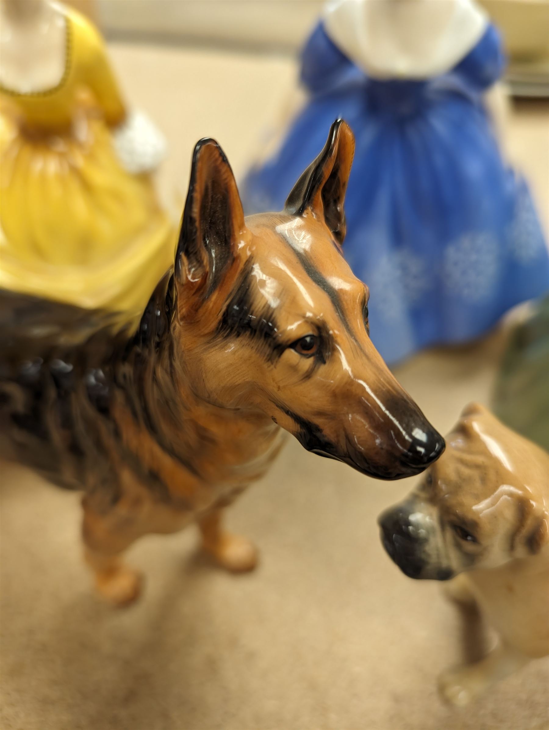 Three Royal Doulton figures, to include Nina, Clarissa and Coralie, together with a Royal Doulton Alsation figure and a Branksome boxer dog figure