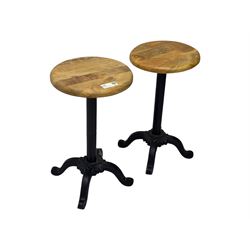 Pair of 20th century machinist stools, each with height-adjustable beechwood circular seats, supported by cast iron pedestal bases with four splayed feet