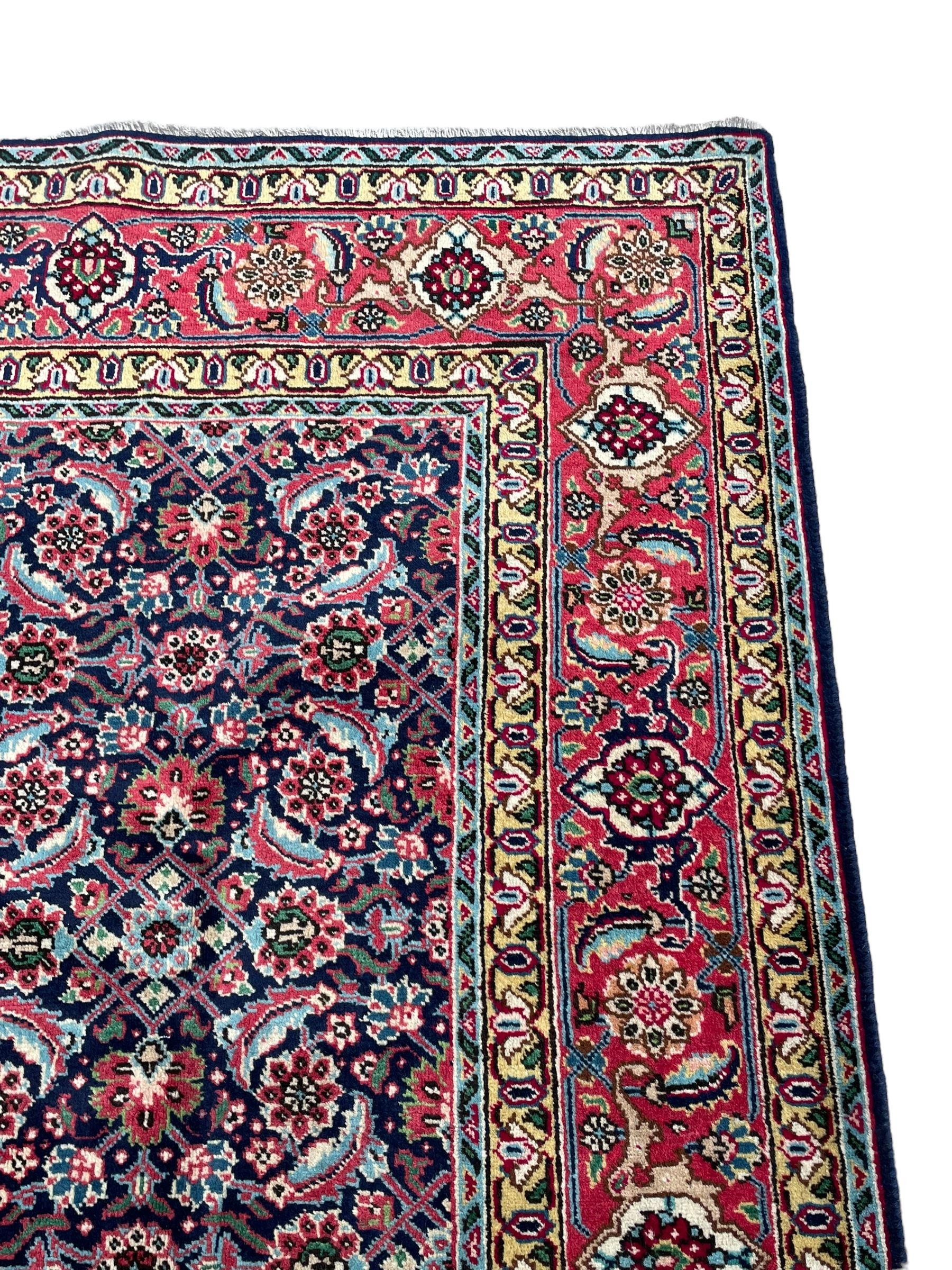 Persian Farahan indigo ground rug, the field decorated with large repeating floral herati motifs, crimson ground border decorated with palmettes and trailing leafy branch, within guard stripes 