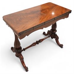 Victorian figured mahogany card table, rectangular swivel and fold-over top with rounded corners and baize lined interior, shaped apron over turned and lobe carved end supports, terminating to scroll and cartouche carved splayed supports united by swell-turned stretcher