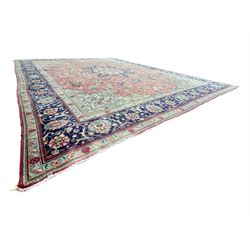 Persian rose ground rug, large central floral medallion surrounded by scrolling foliate and floral motifs, pale green spandrels, wide border in pale green and navy with intricate floral designs, framed by multiple guard stripes with repeating floral and geometric patterns