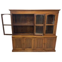 Mid-to-late 20th century Burmese teak wall cabinet, four glazed doors over four panelled doors, on moulded plinth base 