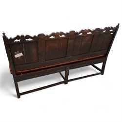 Early 18th century oak hall bench or settle, the cresting rail carved with S-scrolls and crown motifs, over a quadruple panelled back with carved rail, loose seat cushion upholstered in terracotta foliate fabric, flanked by shaped arm terminals, raised on turned supports united by stretchers