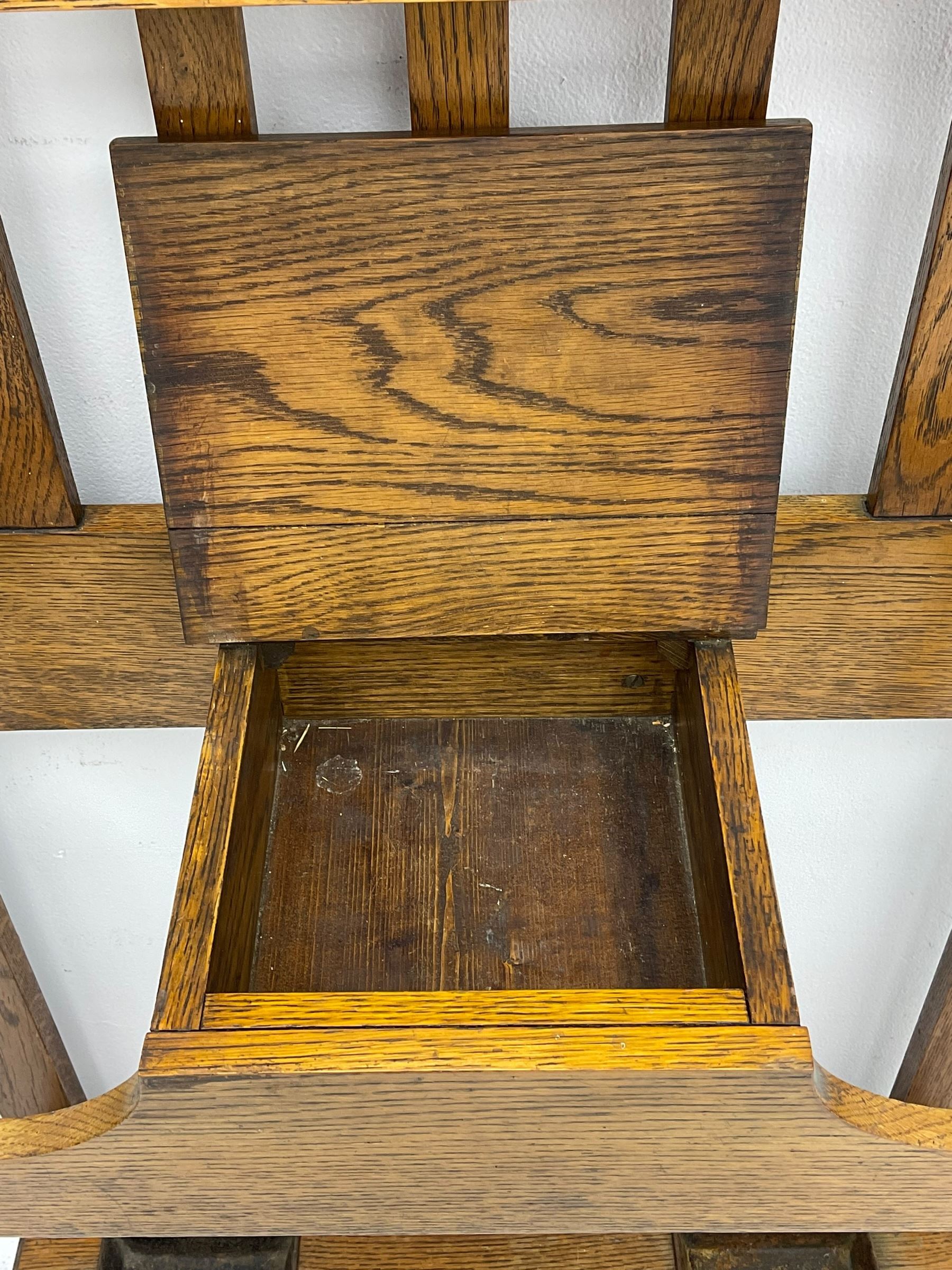 Early 20th century oak hall stand, bevelled mirror back over hinged compartment, on turned front supports 