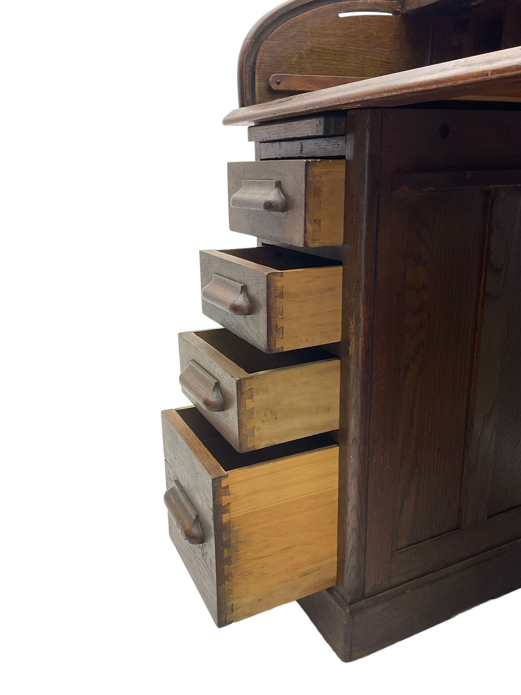 Early 20th century oak twin pedestal roll top desk, tambour roll enclosing fitted interior, each pedestal fitted with four drawers and slide, on plinth base 